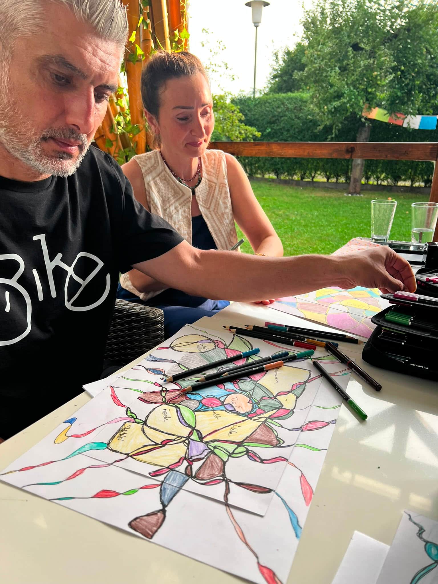 Zwei Menschen zeichnen gemeinsam bei einer NeuroGraphik-Begleitung im Atelier-Garten